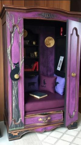 Purple armoire with black cat design and books inside, on a wooden floor. Decorative purple cabinet with open doors, cushions, and a small table inside. Decorative wardrobe with open doors showing a cozy interior with cushions and a small table. Decorative cabinet with a purple interior featuring a cat, moon, and books. Decorative wooden cabinet with open doors, featuring artistic designs and cushions. Upcycled Antique Witchy Cat Moon Armoire Reading Nook \| La Vie Nouveau Décor Shoppe