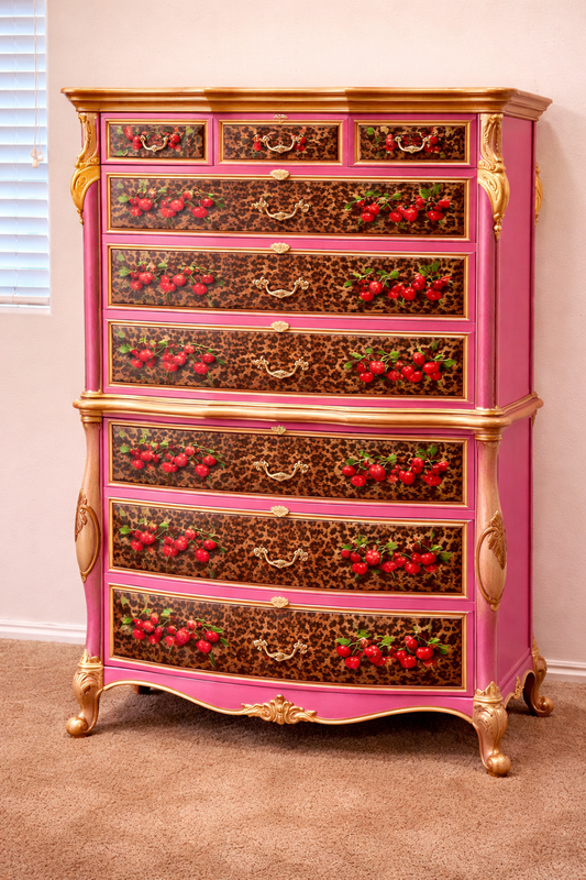 Decorative dresser with pink and gold finish and cherry design on drawers. 	Upcycled Antique Cherry Cheetah Tall Dresser \| La Vie Nouveau Décor Shoppe